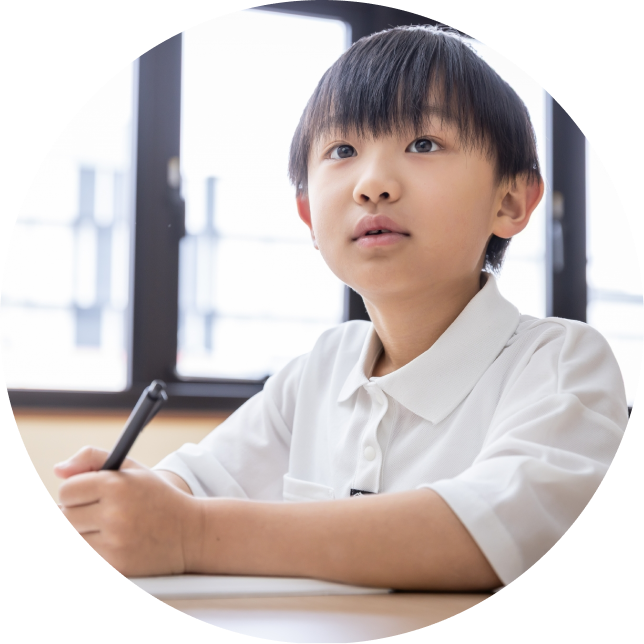 ノートに英単語を書き込み、集中してスペリングの練習をする小学生の男の子