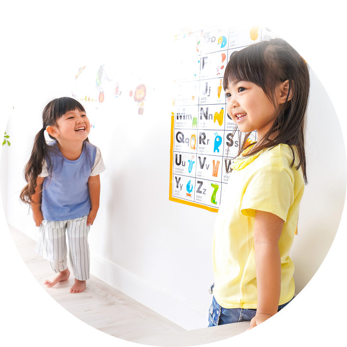 アルファベット表を見ながら、楽しそうに英単語の練習をする女の子
